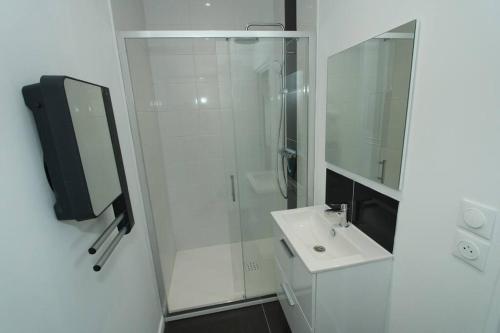 a white bathroom with a shower and a sink at Appartement « La brise de Mer » - 50m de la plage in Bray-Dunes