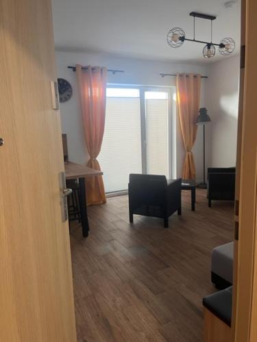 a living room with orange curtains and a table and chairs at Słoneczne Apartamenty in Ustronie Morskie