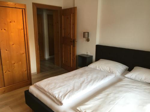 a bedroom with a bed with white sheets at Landhaus Holzereck in Ehrwald