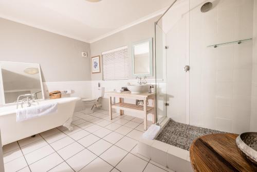 a white bathroom with a tub and a sink at Corner House Residence in Franschhoek