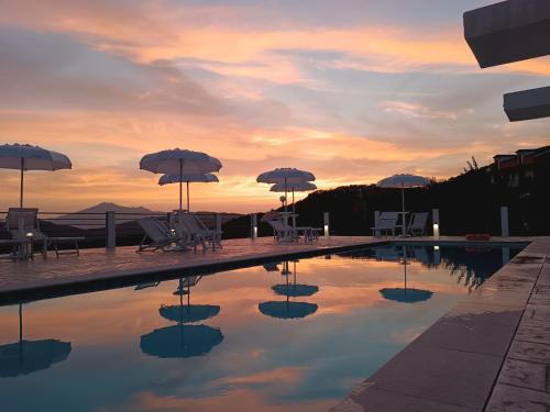 a swimming pool with umbrellas and tables and chairs at Tenuta Vallina - Golfo di Policastro in Tortorella