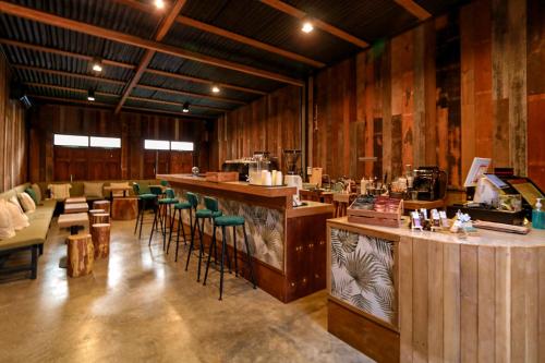 a restaurant with a bar with green chairs and tables at Skugga Farm Cabin in Mae On