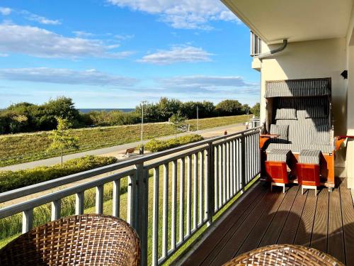a balcony with chairs and a view of a road at Villa Deichgraf Meerblick in Börgerende-Rethwisch