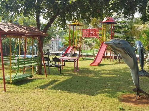 um parque infantil com uma estátua de golfinho na relva em Vasantam Beach Resort em Kashid