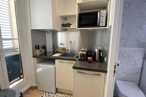 une petite cuisine avec des armoires blanches et un micro-ondes dans l'établissement Appartement 2 pièces (Banane), à Cannes