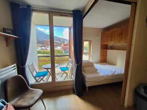 une chambre avec un lit et un balcon avec une table et des chaises dans l'établissement Coup de coeur - Arc 2000 Appartement 4 personnes avec chambre séparée et belle vue sur la montagne, à Bourg-Saint-Maurice