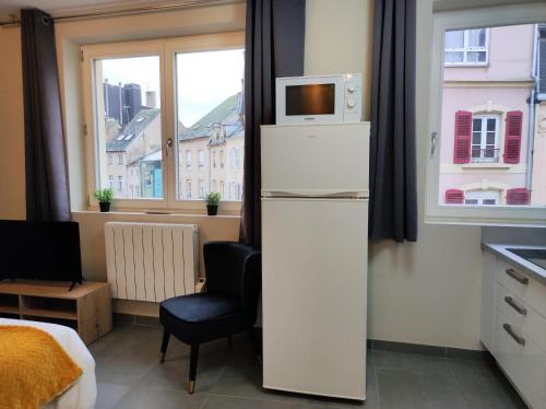 a kitchen with a refrigerator with a microwave on top of it at Le LUX 31 in Thionville