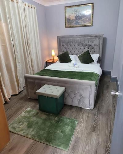 a bedroom with a large bed with a green blanket at Evergreen 2bedroom-sleeps up to 7,2 bathroom in Hornchurch