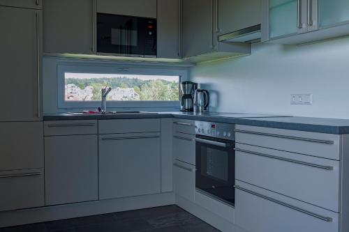 a kitchen with white cabinets and a sink and a window at Ferienhaus Seezeichen in Wasserburg am Bodensee