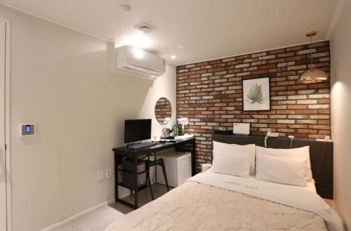 sypialnia z ceglaną ścianą, łóżkiem i biurkiem w obiekcie Hotel Soo w Seulu