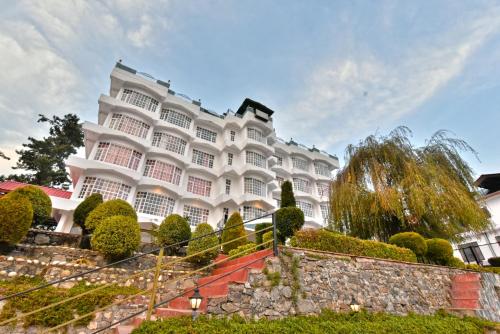 a large white building with trees and bushes at Hillcrest Resort by DLS Hotels in Shimla
