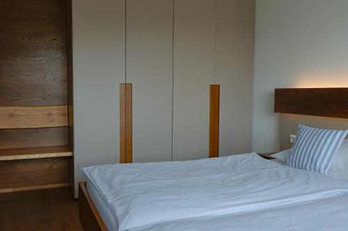 a bed with white sheets and a blue pillow at Ferienhaus Seezeichen in Wasserburg am Bodensee