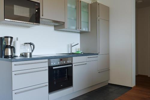 a kitchen with white cabinets and a black oven at Ferienhaus Seezeichen in Wasserburg am Bodensee