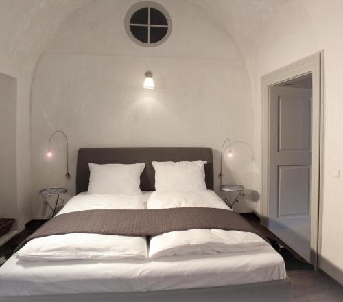 1 dormitorio con 1 cama grande con almohadas blancas en Gavalier Design Rooms, en Banská Štiavnica