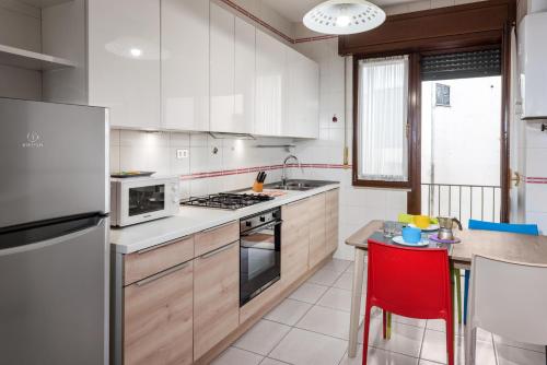 cocina con electrodomésticos blancos y taburete rojo en Flats4Rent Lucia, en Verona