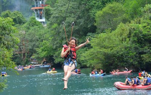 a woman is hanging on to a rope on a river at Discovery Lodge Phong Nha in Cừ Lạc