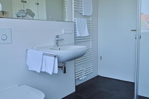 a white bathroom with a sink and towels at Ferienhaus Seezeichen in Wasserburg am Bodensee