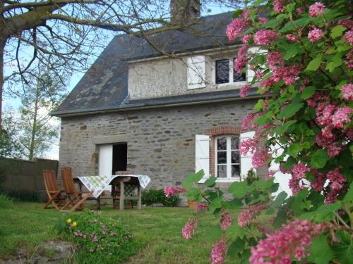 an old stone house with pink flowers in the yard at Entre Mont St Michel et Merveille in Vains