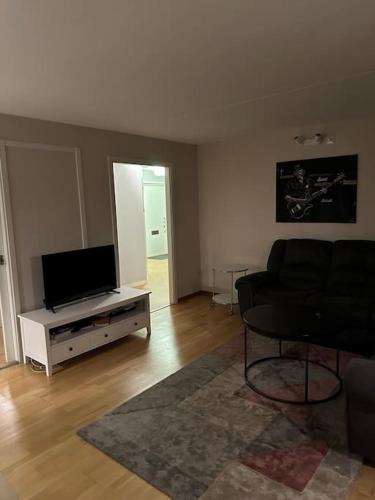 ein Wohnzimmer mit einem Sofa und einem Flachbild-TV in der Unterkunft Trevlig lägenhet i Kista in Stockholm