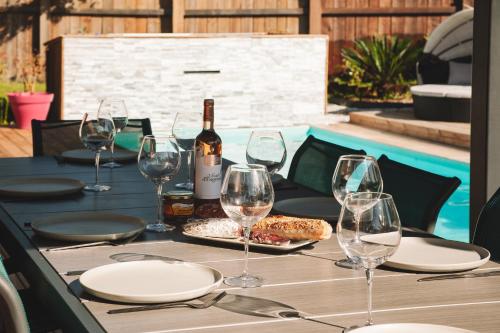 a table with a bottle of wine and wine glasses at VILLA DREAM LANDES Piscine tempérée-Jacuzzi-5 suites parentales in Moliets-et-Maa
