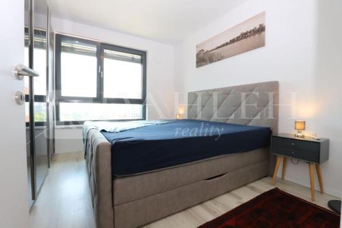 a bedroom with a bed with a blue bedspread and a window at Einpark Fabulous Apartment with Private parking in Bratislava