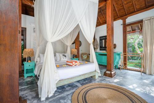 a bedroom with a canopy bed with white drapes at Villa Almar in Dalung
