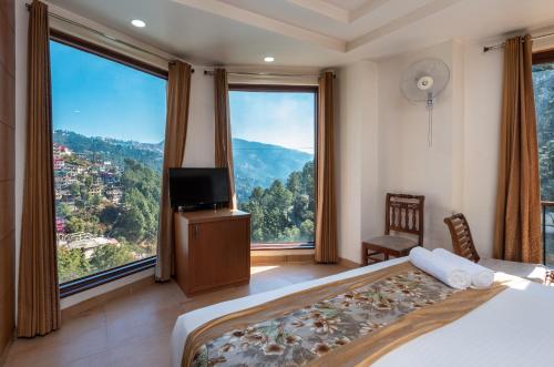 a bedroom with a bed and a tv and large windows at Rock Castle By DLS Hotels in Shimla