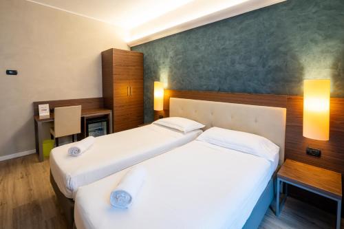 a hotel room with two beds and a desk at Hotel Des Etrangers in Milan