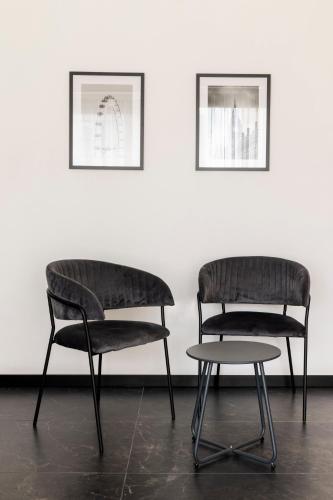 two chairs and a table in front of a white wall at The Londoner Hotel St. Julian's in St Julian's