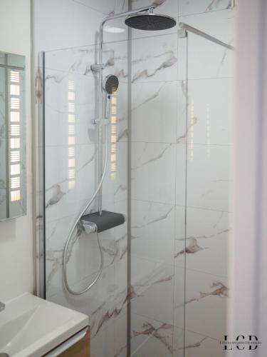 une douche avec une porte vitrée dans une salle de bain dans l'établissement Le Métropolitan, à Dijon