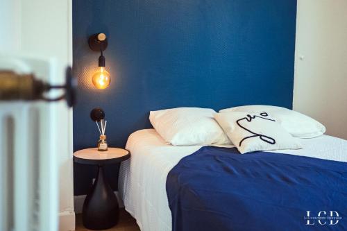 une chambre avec un lit avec un mur bleu dans l'établissement Le Métropolitan, à Dijon