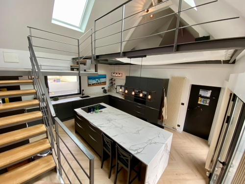 une cuisine avec un grand comptoir blanc et des escaliers dans l'établissement Villa Clin d'œil - Villa De knipoog, à Wimereux