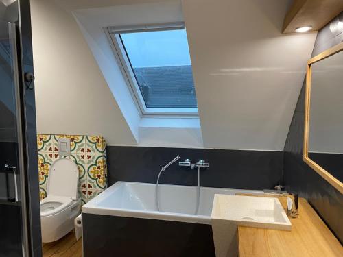 une salle de bain avec baignoire et toilettes et une fenêtre dans l'établissement Villa Clin d'œil - Villa De knipoog, à Wimereux