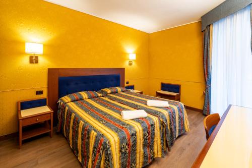 a hotel room with a bed with yellow walls at Hotel Des Etrangers in Milan