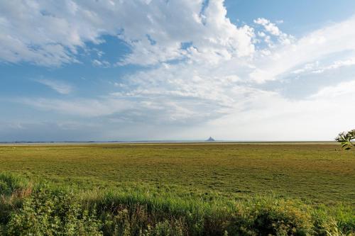 a large field of grass with a cloudy sky at Entre Mont St Michel et Merveille in Vains