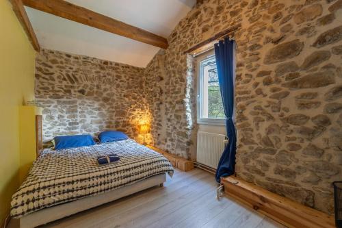 une chambre avec un lit dans un mur de pierre dans l'établissement Mas cévennol - Belle maison 3 chambres, à Saint-Florent-sur-Auzonnet
