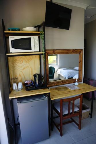 a small kitchen with a table and a microwave and a refrigerator at Nabana Lodge in Hazyview