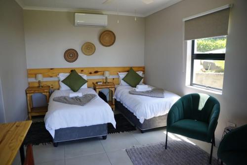 a bedroom with two beds and a chair and a window at Nabana Lodge in Hazyview