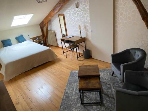 1 dormitorio con 1 cama, escritorio y sillas en Le Petit Bleu Chambre d'hôtes, en Bourg-de-Visa