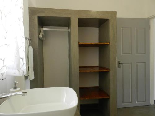 La salle de bains est pourvue d'une baignoire blanche et d'un lavabo. dans l'établissement President Paul Kruger Guest Lodge, à Rustenburg