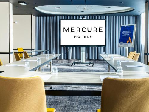 a conference room with tables and chairs and a screen at Mercure Dijon Centre Clemenceau in Dijon