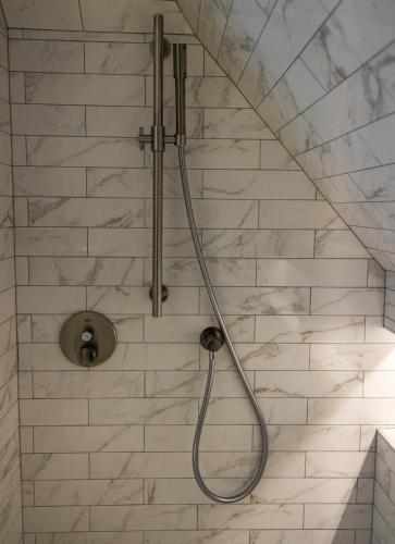a shower with a hose attached to a wall at Oakvale Villa Sand in Åhus