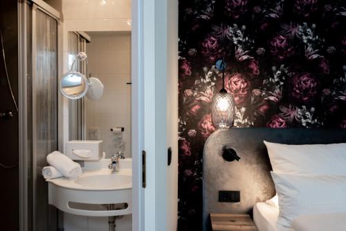 La salle de bains est pourvue d'un lavabo et d'un papier peint à fleurs. dans l'établissement Parkhotel, à Bad Waldsee