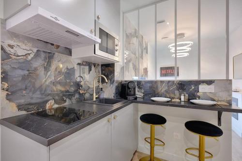 une cuisine avec des placards blancs et deux tabourets de bar jaunes dans l'établissement Welcome to Dubai / Jacuzzi, à Ivry-sur-Seine