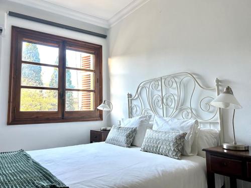 a white bedroom with a white bed and a window at Hispalis Alfonso X in Seville