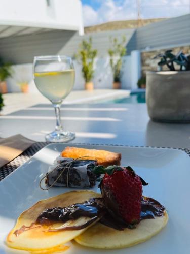 a plate of food and a glass of white wine at Lithos Luxury Suites in Tinos Town