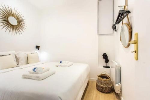 une chambre avec un lit blanc avec des serviettes dessus dans l'établissement St Germain-Bon Marché - cosy n°1, à Paris