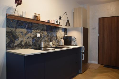 a kitchen with a black counter and a refrigerator at Warsaw City Break II in Pruszków