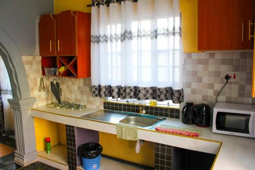 una pequeña cocina con fregadero y microondas en Hotfoot Homestays, en Kiganjo