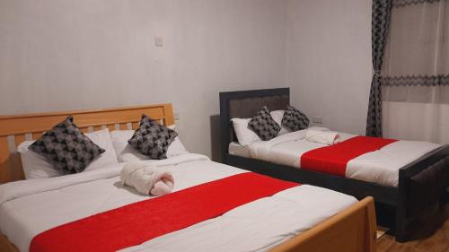 a bedroom with two beds with red and white sheets at Hotfoot Homestays in Kiganjo